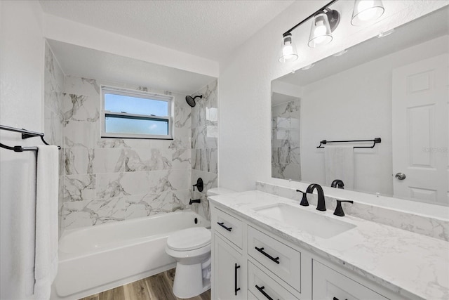 bathroom with toilet, vanity, bathtub / shower combination, wood finished floors, and a textured ceiling