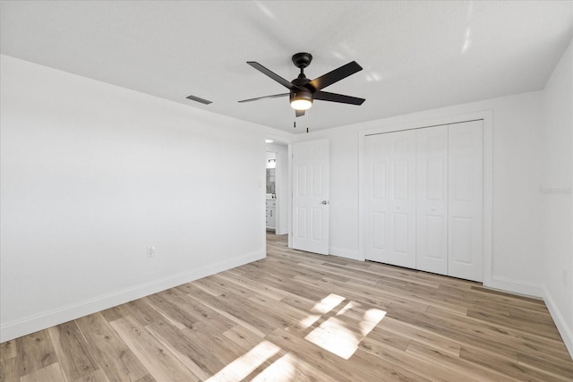 unfurnished bedroom with visible vents, a closet, light wood finished floors, baseboards, and ceiling fan