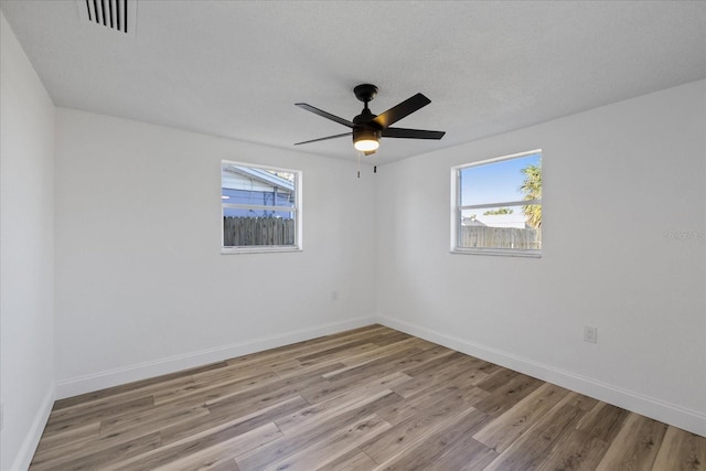 spare room with baseboards, light wood-style floors, and a healthy amount of sunlight