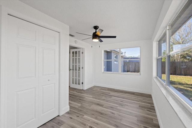 spare room featuring visible vents, baseboards, a ceiling fan, and wood finished floors
