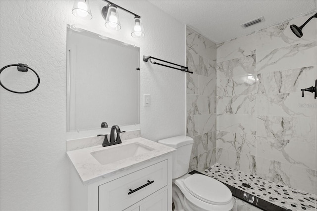 full bath featuring toilet, a shower stall, vanity, and a textured wall