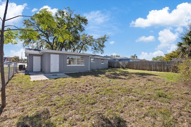 back of house featuring a fenced backyard, stucco siding, and a yard