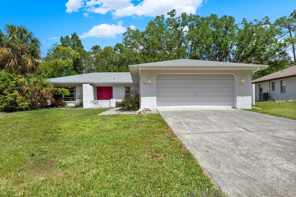 ranch-style house featuring an attached garage, stucco siding, driveway, and a front lawn