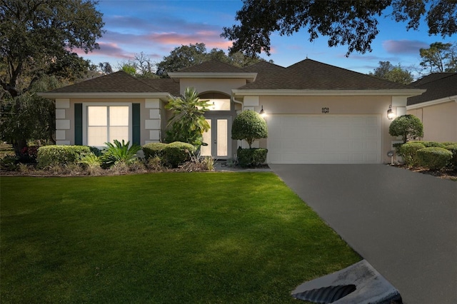 view of front of home with stucco siding, driveway, an attached garage, and a yard