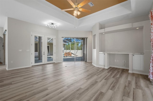 unfurnished room featuring visible vents, a tray ceiling, wood finished floors, french doors, and baseboards