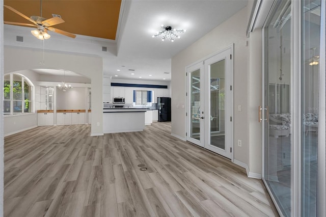 unfurnished living room featuring visible vents, baseboards, arched walkways, and light wood-style flooring