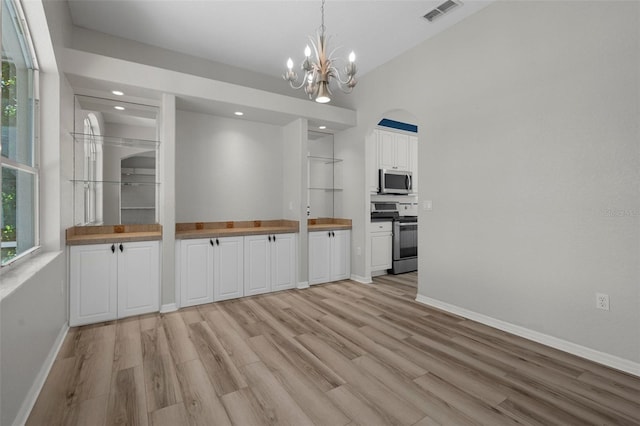 unfurnished dining area with an inviting chandelier, baseboards, visible vents, and light wood finished floors