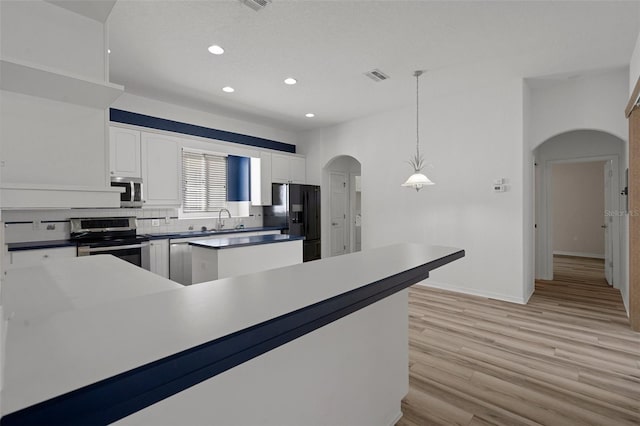 kitchen with visible vents, arched walkways, white cabinets, stainless steel appliances, and a sink