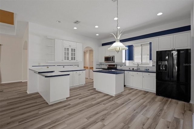 kitchen featuring visible vents, open shelves, dark countertops, arched walkways, and appliances with stainless steel finishes