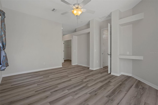 unfurnished living room with a ceiling fan, visible vents, wood finished floors, and baseboards