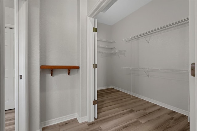 walk in closet with wood finished floors