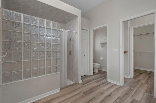 full bathroom featuring baseboards, toilet, walk in shower, and wood finished floors