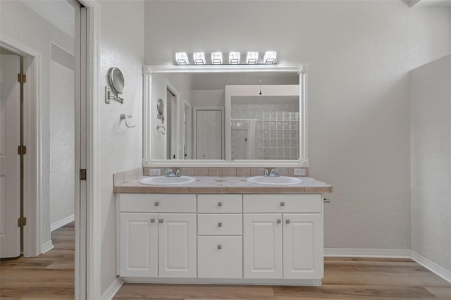 full bathroom with a sink, wood finished floors, and a shower stall