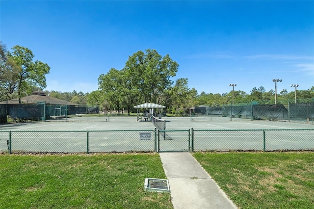 view of sport court with a gate, fence, and a lawn