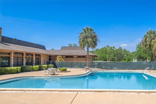 pool with a patio area and fence