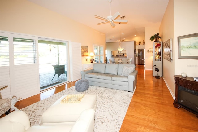 living room with visible vents, high vaulted ceiling, a ceiling fan, light wood finished floors, and baseboards