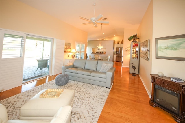 living room with vaulted ceiling, baseboards, light wood finished floors, and ceiling fan