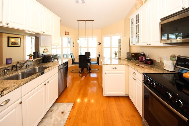 kitchen featuring light wood finished floors, glass insert cabinets, white cabinets, stainless steel appliances, and a sink