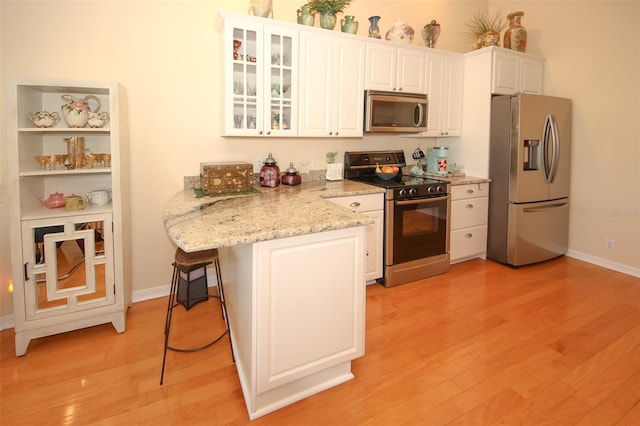 kitchen with a breakfast bar, light wood-style flooring, white cabinetry, and stainless steel appliances