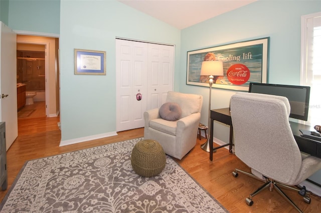 office area featuring vaulted ceiling, wood finished floors, and baseboards