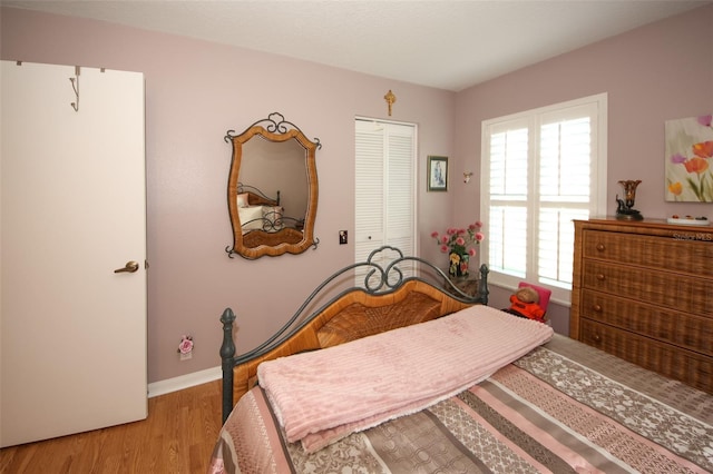 bedroom featuring baseboards, light wood-type flooring, and a closet