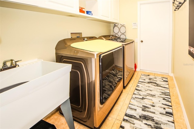 laundry area featuring baseboards, light tile patterned floors, washer and dryer, cabinet space, and a sink