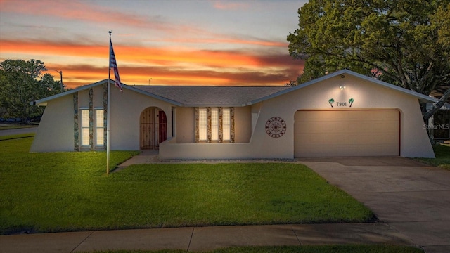 view of front facade featuring stucco siding, a lawn, concrete driveway, and an attached garage