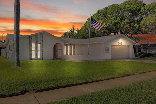 view of front of house with stucco siding, concrete driveway, a lawn, and a garage