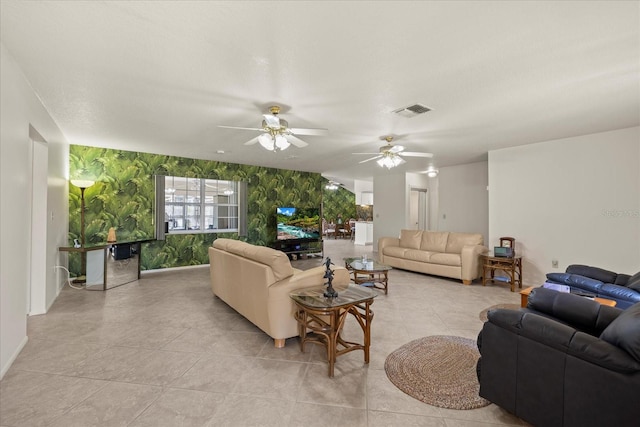 living room featuring visible vents, wallpapered walls, an accent wall, light tile patterned floors, and a ceiling fan