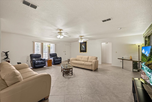 living area featuring light tile patterned flooring, visible vents, a textured ceiling, and ceiling fan