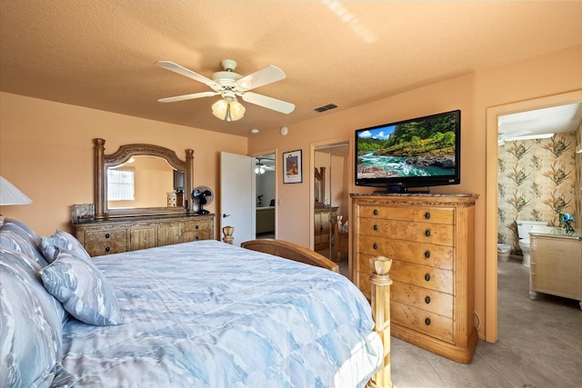 bedroom with ensuite bath, a ceiling fan, visible vents, and a textured ceiling