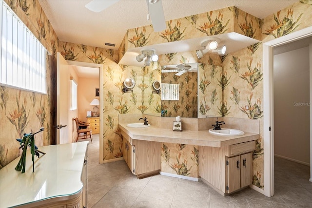 full bath with a sink, a textured ceiling, tile patterned flooring, and wallpapered walls