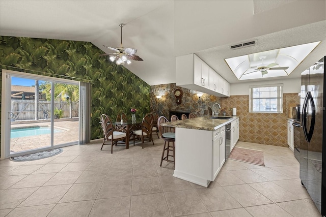 kitchen with a sink, visible vents, ceiling fan, and freestanding refrigerator