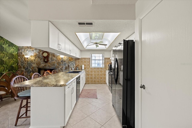 kitchen with a kitchen bar, visible vents, black appliances, a sink, and a textured ceiling