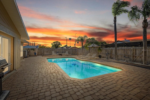 pool at dusk with a fenced backyard, a fenced in pool, and a patio