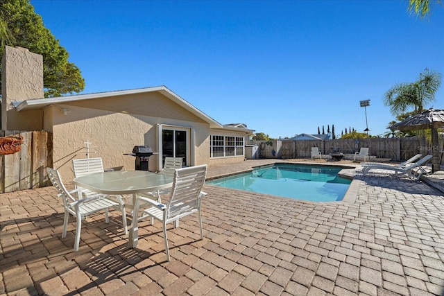 view of swimming pool featuring a fenced in pool, outdoor dining area, a fenced backyard, a patio area, and area for grilling