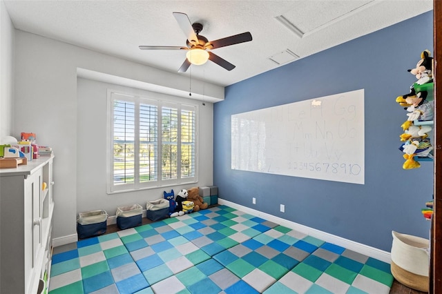 playroom with attic access, baseboards, visible vents, and a textured ceiling