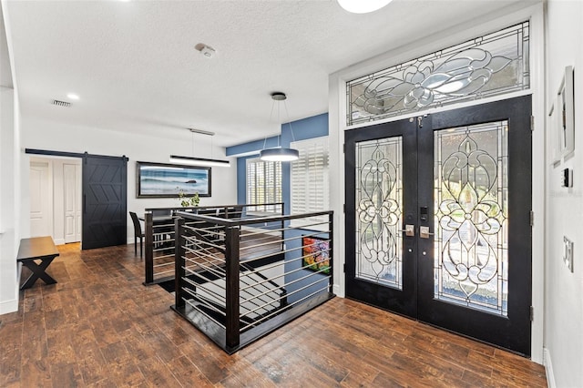 foyer featuring a textured ceiling, wood finished floors, a barn door, french doors, and baseboards