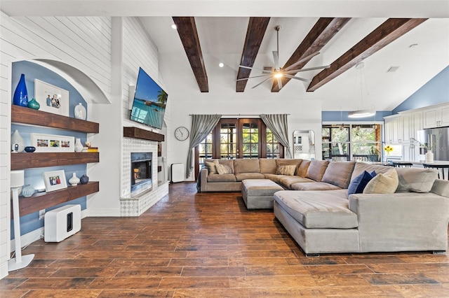 living area with wood finished floors, visible vents, beamed ceiling, high vaulted ceiling, and a brick fireplace