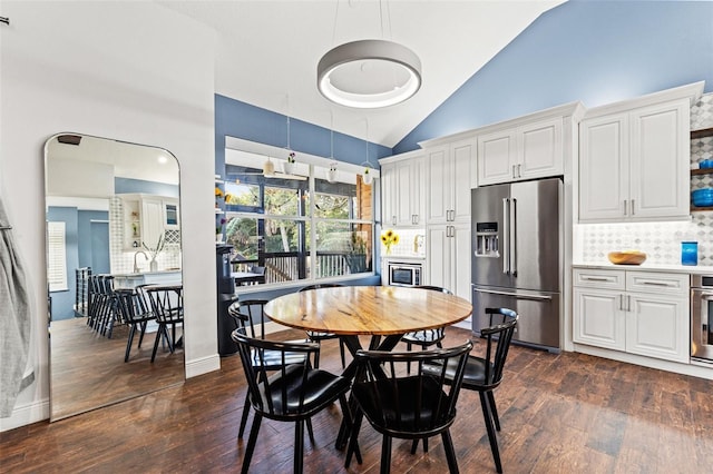 dining area with high vaulted ceiling and dark wood finished floors