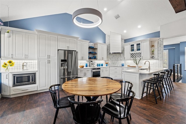 kitchen featuring open shelves, light countertops, stainless steel appliances, wall chimney exhaust hood, and dark wood-style flooring