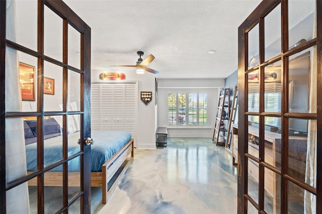 bedroom featuring french doors, baseboards, a textured ceiling, and finished concrete floors