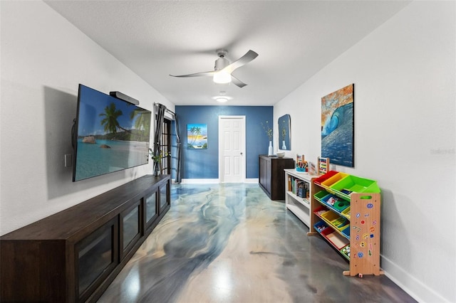 interior space with a ceiling fan, baseboards, concrete flooring, and a textured ceiling