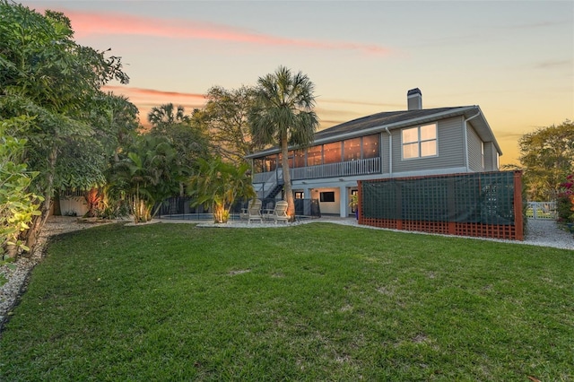 back of property with stairway, a patio, a lawn, and a sunroom