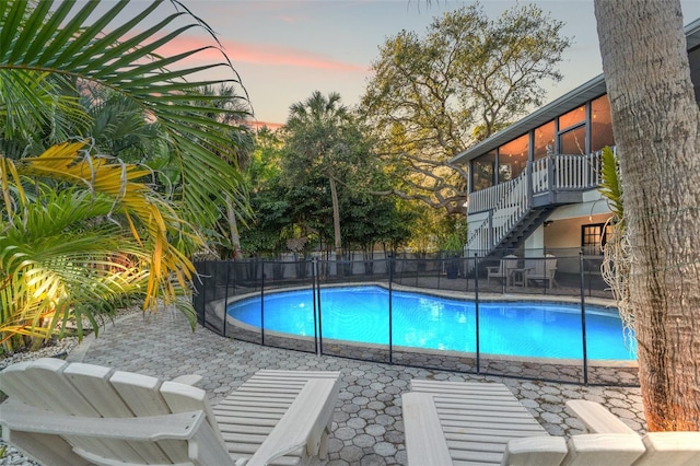 view of pool featuring a fenced in pool, fence, stairway, a sunroom, and a patio area