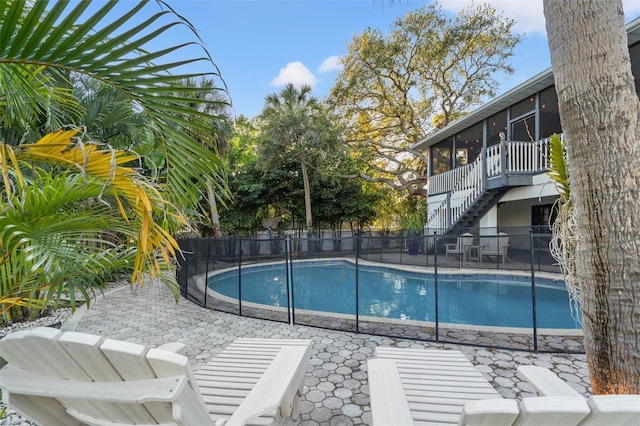 view of swimming pool with stairway, fence, a patio, and a sunroom