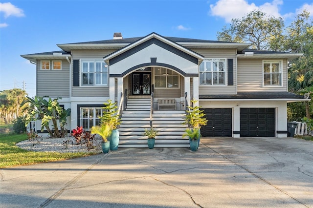 view of front of home with stairway, concrete driveway, covered porch, french doors, and a garage