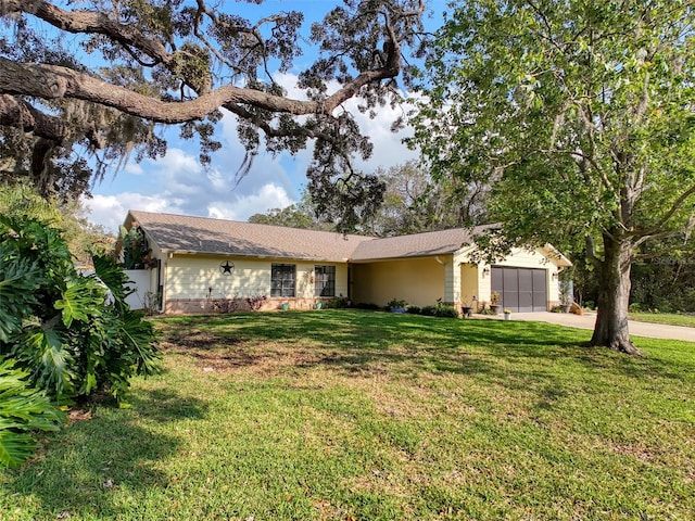 ranch-style home featuring a garage, concrete driveway, and a front lawn