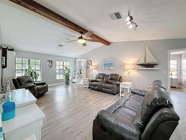 living area featuring light wood-type flooring, visible vents, a textured ceiling, and vaulted ceiling with beams