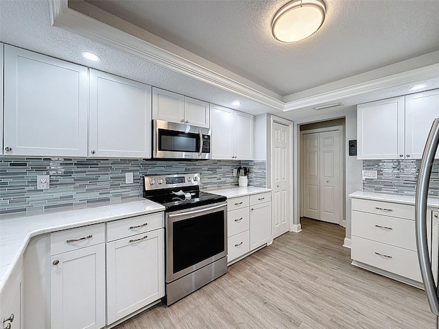 kitchen featuring white cabinetry, light countertops, light wood-style flooring, appliances with stainless steel finishes, and a textured ceiling